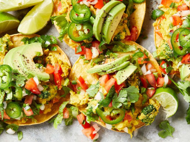 Breakfast Tostadas topped with salsa and lime wedges on a marble countertop