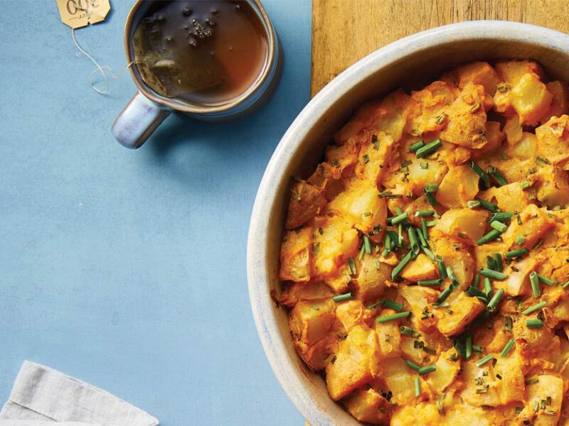 Cheesy Vegan Potato Casserole in a white bowl against a blue background