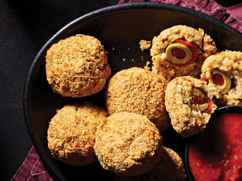 Air-Fried Arancini in a black ceramic bowl served with a side of marinara sauce