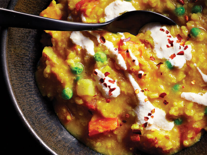 Khichdi (Spiced Lentil and Rice Porridge) in a gray ceramic bowl with a black metal spoon