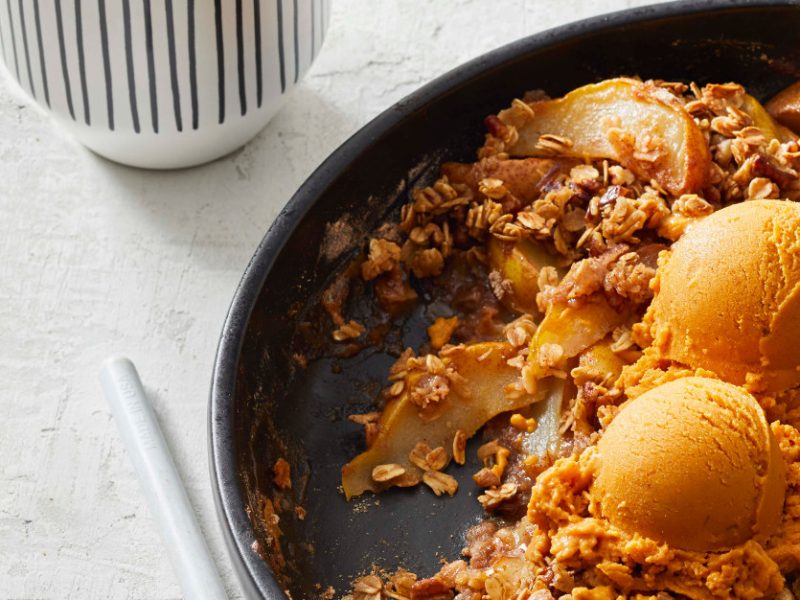 Maple-Ginger Spiced Pear Crisp with Oats in a cast-iron skillet on a marble countertop