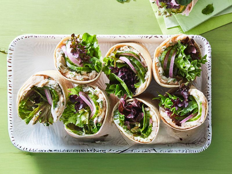 White Bean Wraps with Pickled Cucumber and Mint cut in half, arranged on a white platter, with cut side up