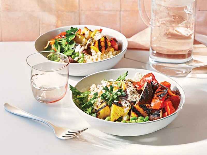 Grilled Pineapple Veggie Bowl in two bowls on a white table setting with a peach background