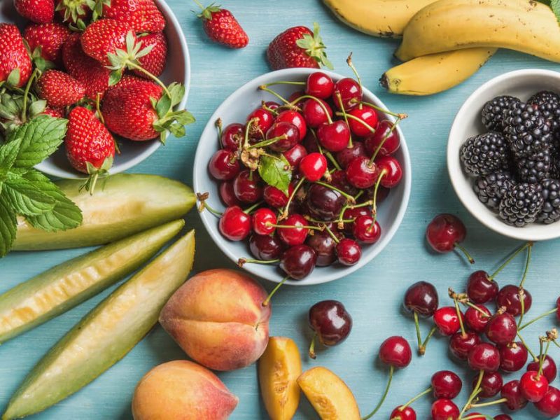 Healthy summer fruit variety on blue wooden backdrop